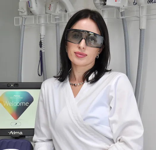 Professional aesthetic clinic specialist wearing laser safety glasses beside advanced skin treatment equipment.