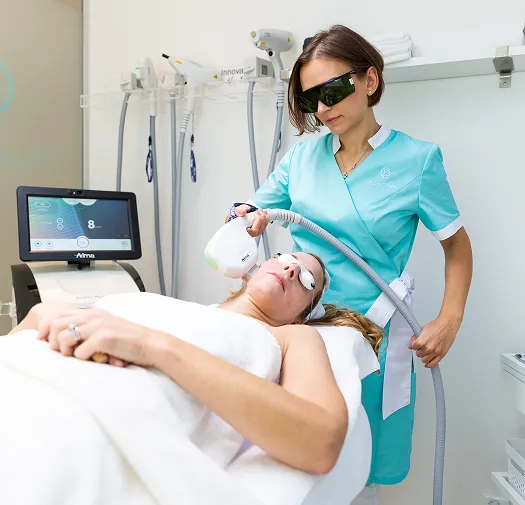 A skincare specialist performing a professional laser skin treatment on a patient using advanced aesthetic technology in a modern clinic.