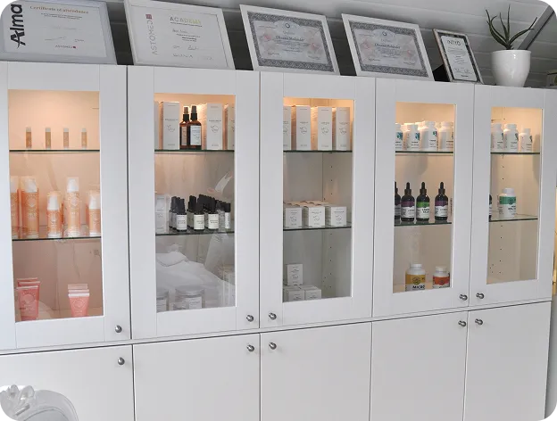 Professional skincare products and treatment solutions displayed in a modern aesthetic clinic cabinet.